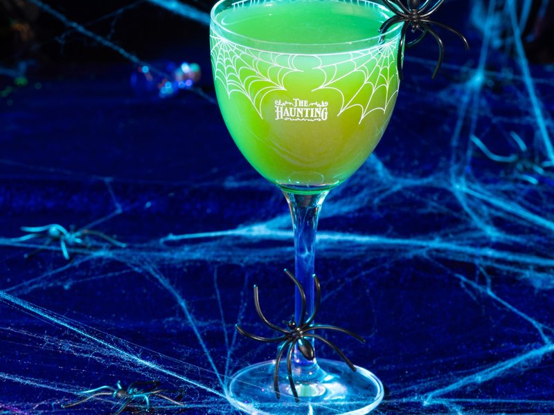 Green cocktail and spooky doll displayed for The Haunting at Starbird