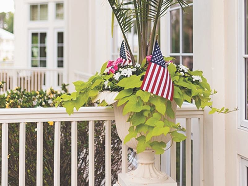 Flag sticks in a white planter with greens and flowers