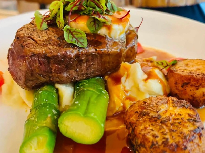 Filet mignon topped with blackened scallops and served with vegetables