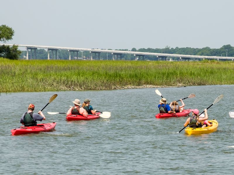 People in kayaks on the water in Hilton Head Island, SC, with the bridge in the background