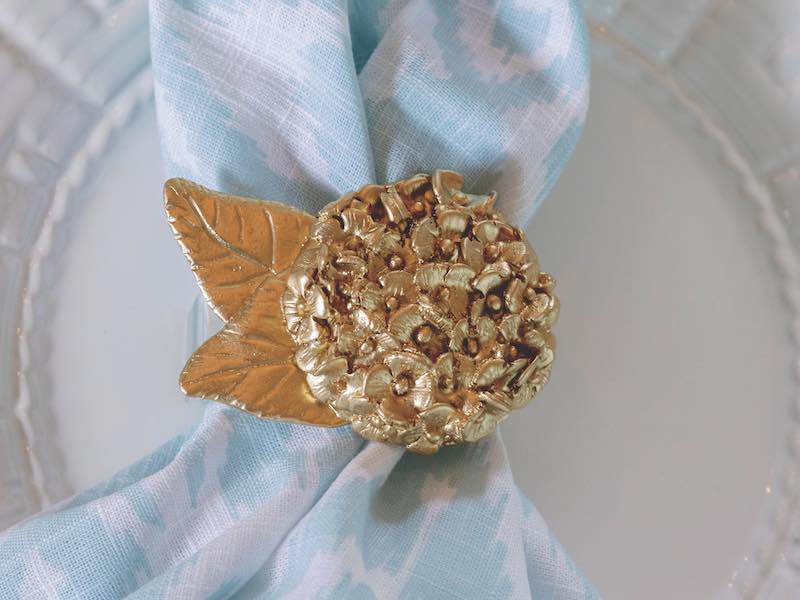 Gold napkin ring on cloth napkin with white plate