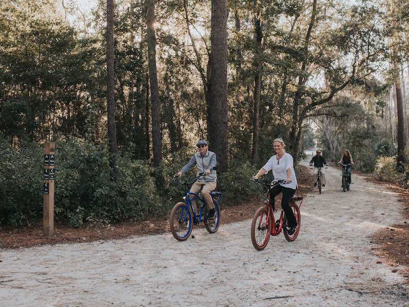 People riding on a bike trail with trees in the background