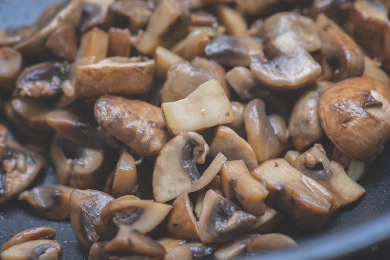 Close up view of sauteed slices of Common Mushrooms (Agaricus bisporus) cooking in the pan