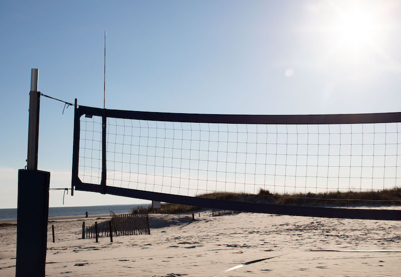 Volleyball Net on Beach with Sun in the background 