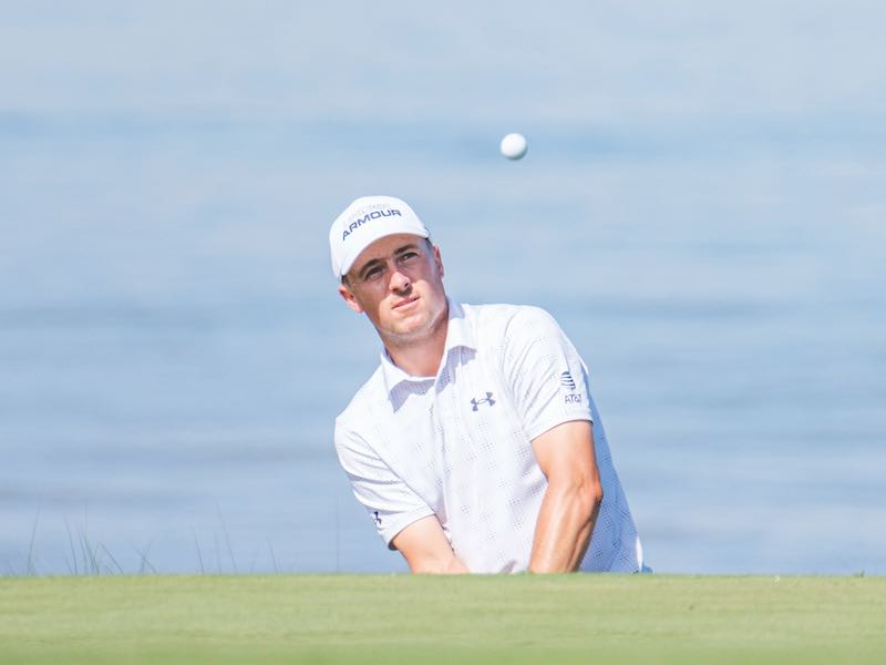 Jordan Spieth hitting a golf ball at the RBC Heritage with water in the background and the ball in the air