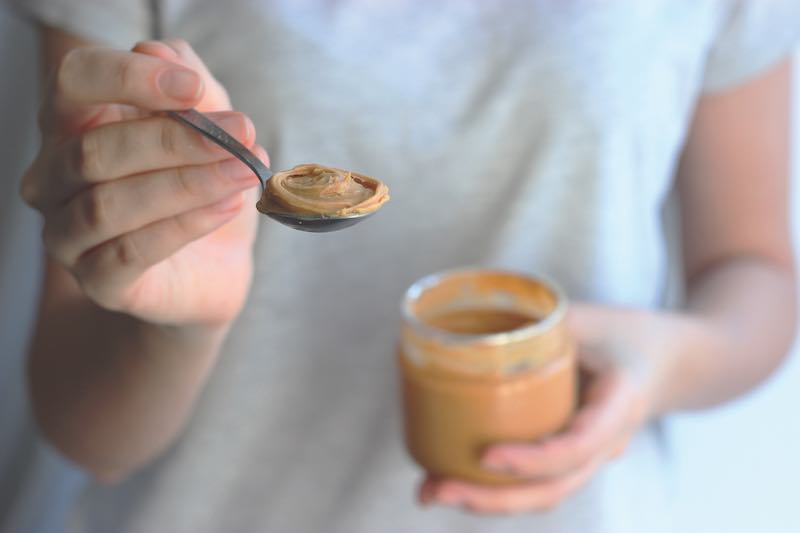 Nut paste in female hands on a light background.