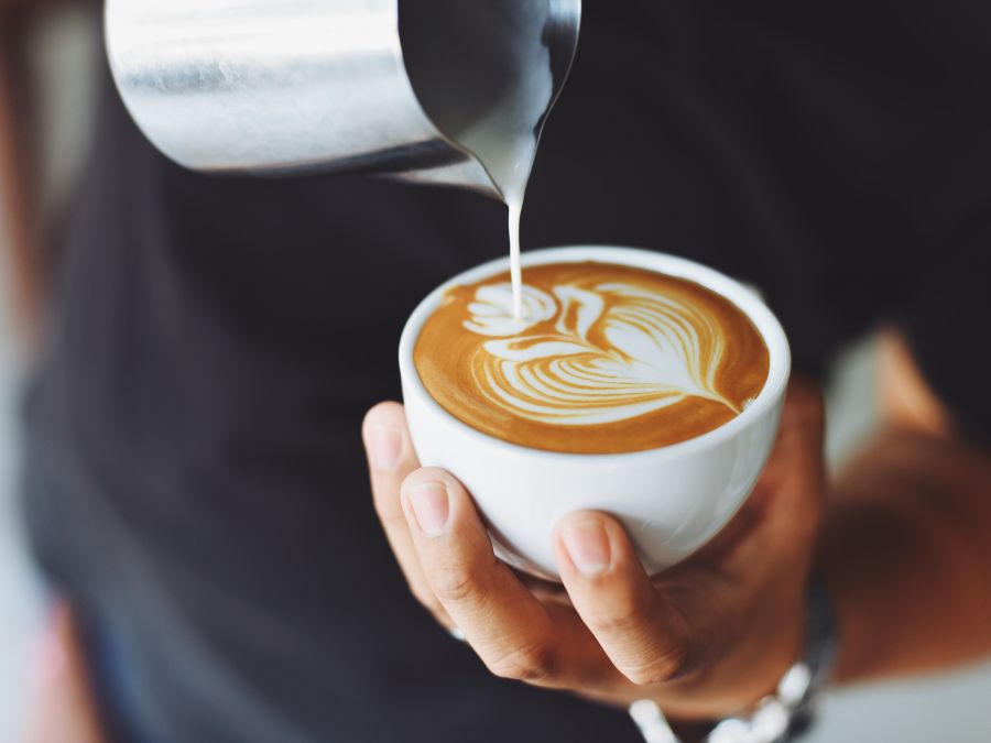 Coffee design being poured on a cup of a coffee while a man holds it