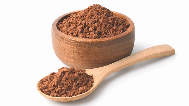Cocoa powder in wooden bowl and spoon isolated on white background.