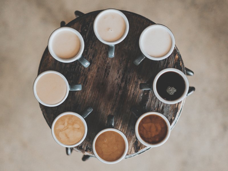 Different kinds of coffee in coffee cups on a wooden surface - overhead shot