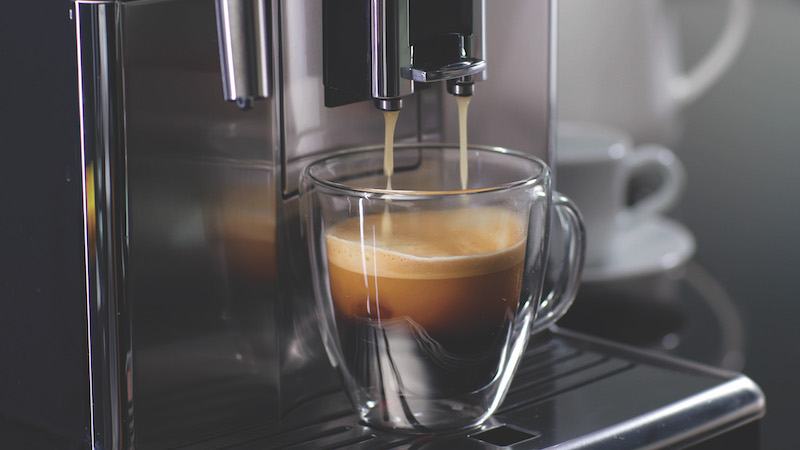 Coffee machine filling a cup with expresso. Transparent mug in automated coffeemaker machine. Beverage drink for breakfast