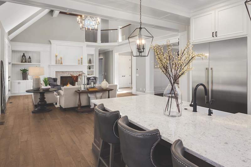 Beautiful kitchen and living room in new traditional style luxury home. Features vaulted ceilings, fireplace with roaring fire, and elegant furnishings.