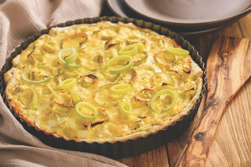 Quiche with leek and cheese on brown background