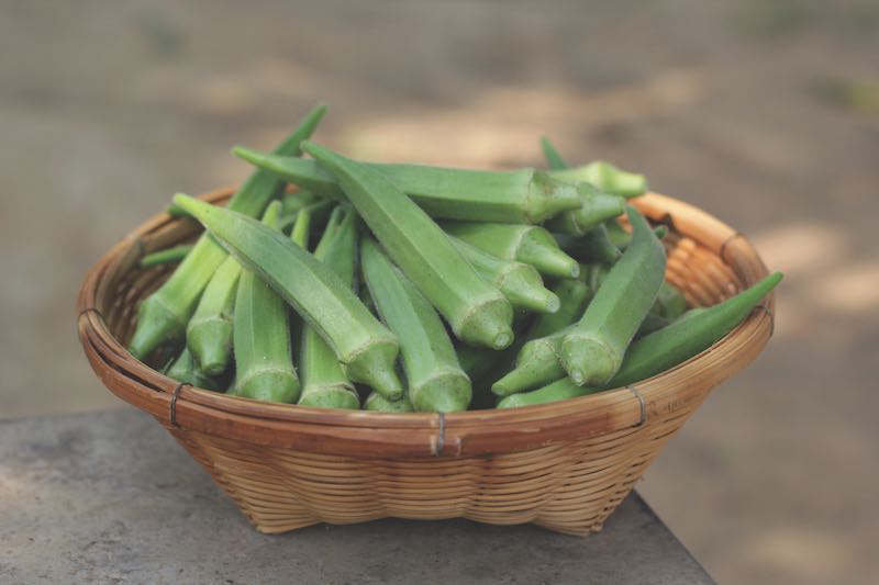 fresh green okra on a woven basket close up and top view