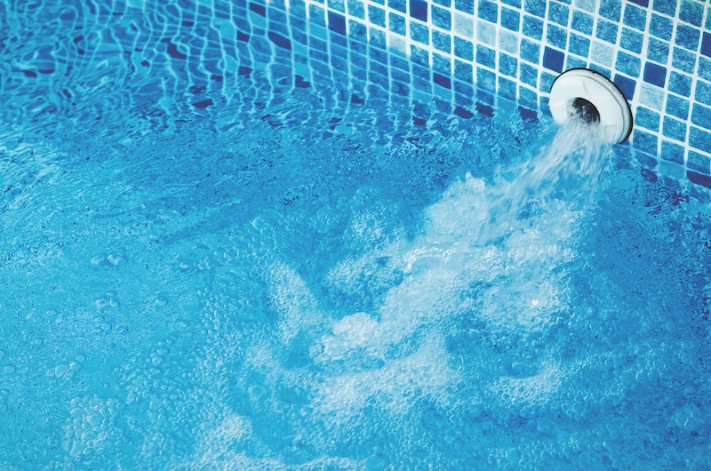 Top view of an active underwater discharge nozzle filtration system set in a blue liner swimming pool with low water level ready for winter.