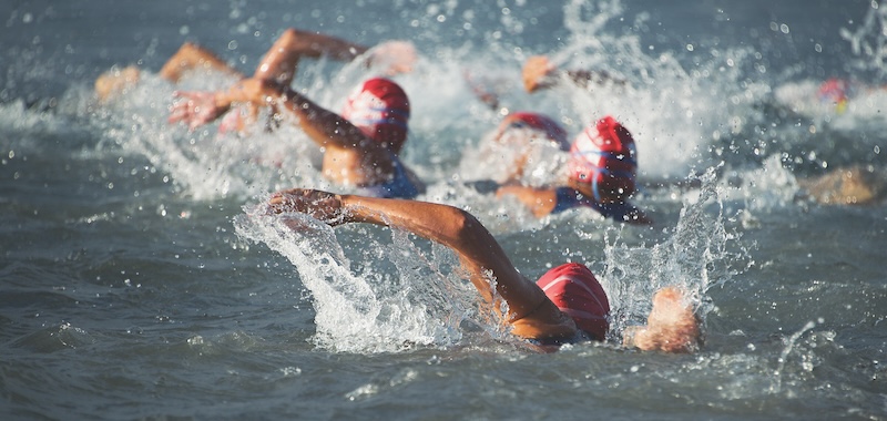 Competitors swimming out into open water at the beginning of triathlon