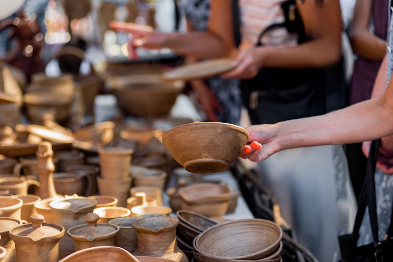 Customer buying decorative ceramic plates on street market, small business, outdoor street sale in the context of the coronavirus pandemic lockdown