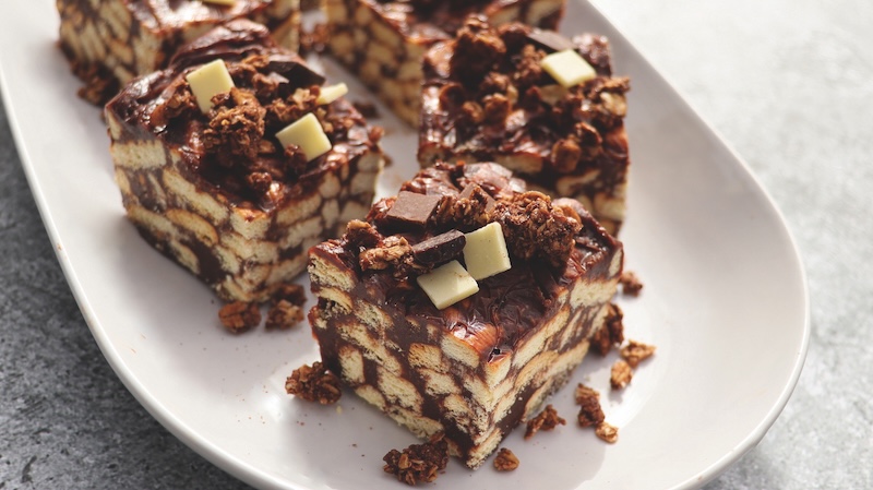 Lazy cake or mosaic cake with granola and chocolate . Homemade no bake chocolate biscuit cake on a table .