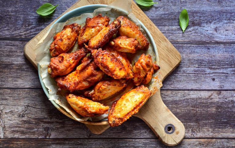 Crispy wings on a plate on top of a cutting board