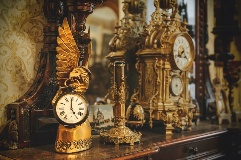 Old vintage antique bronze clock and utensil on wooden shelf, Antiques concept, toned