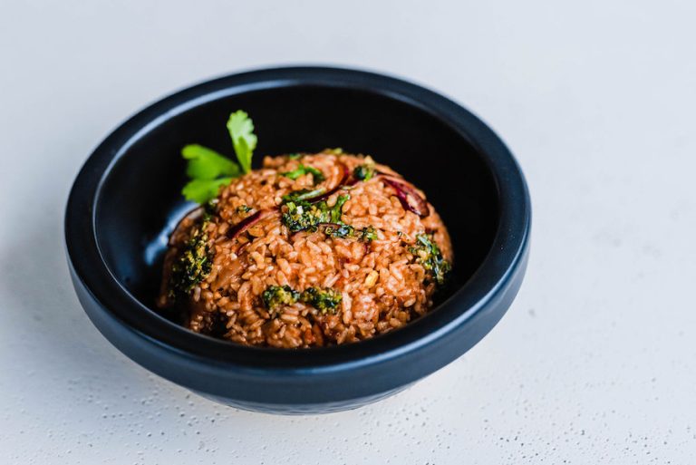 A pot of vibrant red Jollof rice with tomatoes, peppers, and herbs”