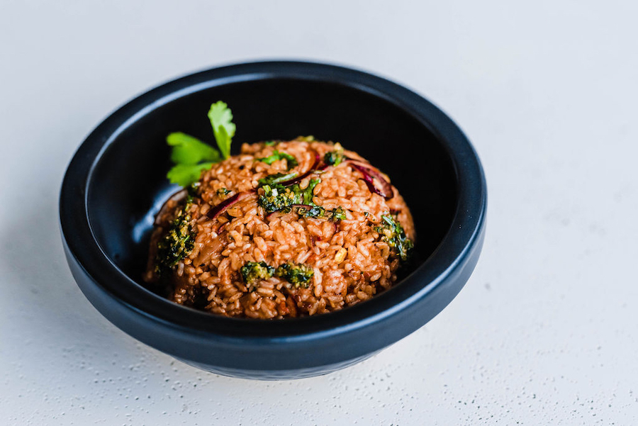 A pot of vibrant red Jollof rice with tomatoes, peppers, and herbs”