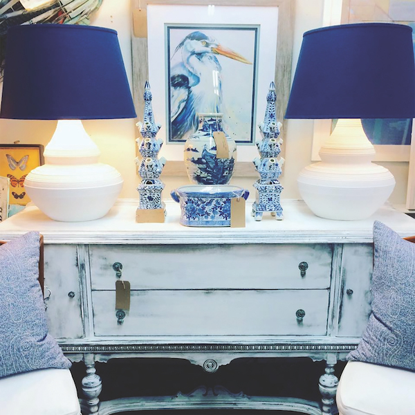 Coastal Exchange antique dresser with blue decorative lamps, sculptures and crane painting.