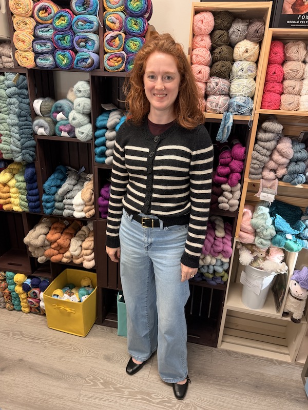 Caitlin Piette stands with her yarn collection knitting crocheting