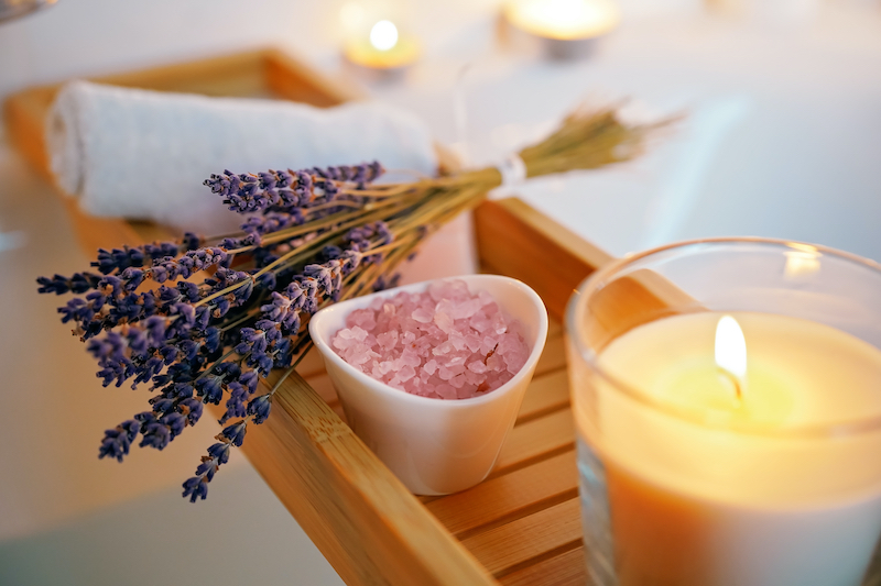 Lavendar and bath salts with candle over calming bath