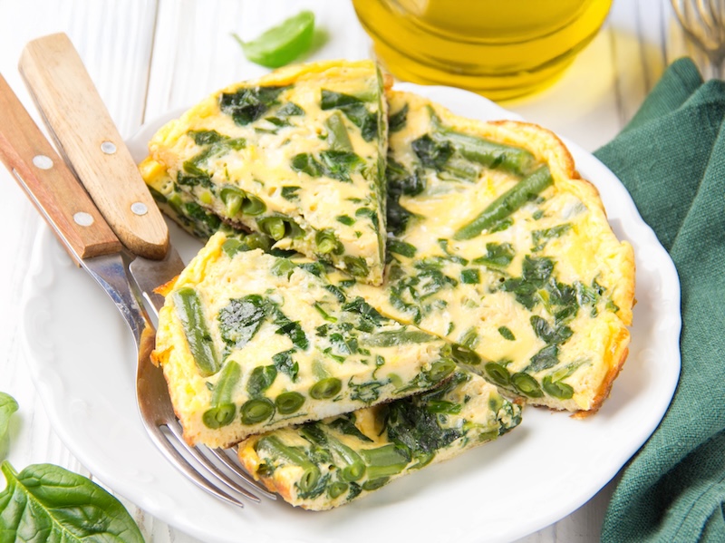 Omelet with spinach and green beans, healthy food. Egg and milk Frittata, delicious Breakfast on white wooden background