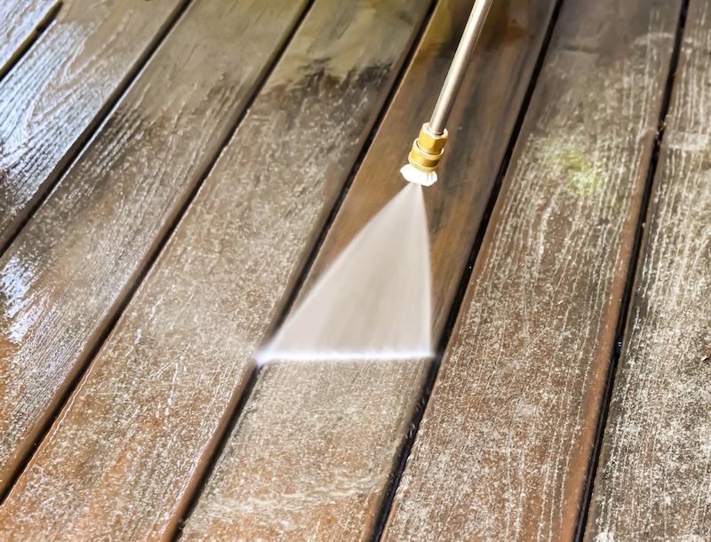 A power washer washing a deck
