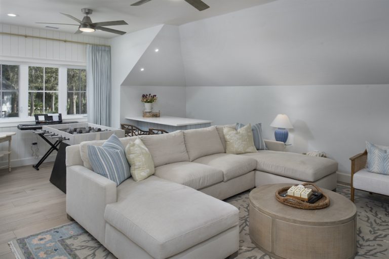 Sea Pines entertainment room by RCH Construction with muted blue palette, large couch, foosball table and games