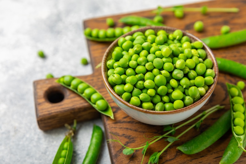 Fresh green pea pods with green peas on a wooden background. Sweet green peas. Green pea beans vegetables. Vegan. healthy vegetable. Copy space