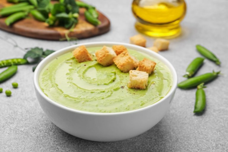 Tasty pea cream soup with croutons served on grey table, closeup