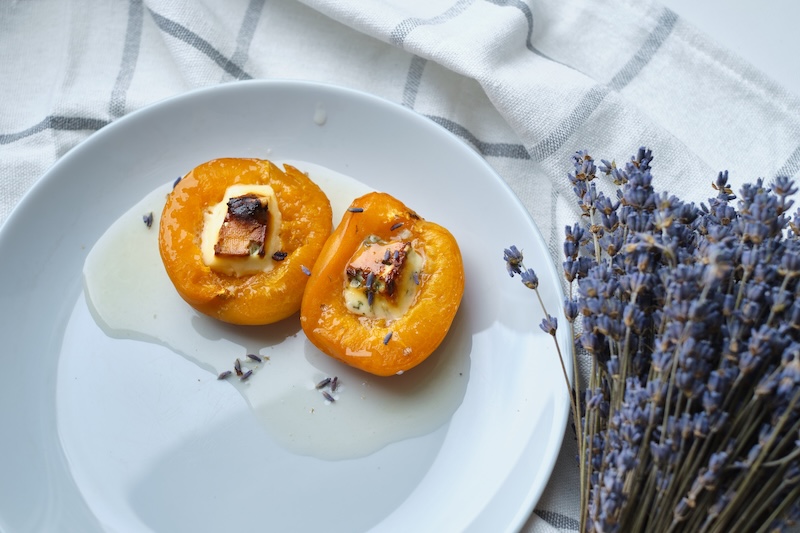 Apricots or peaches baked with blue cheese and lavender sprigs. Delicious dessert with fruits and cheese.Light background, banner, catering menu recipe, place for text. Sweet dessert with fruits