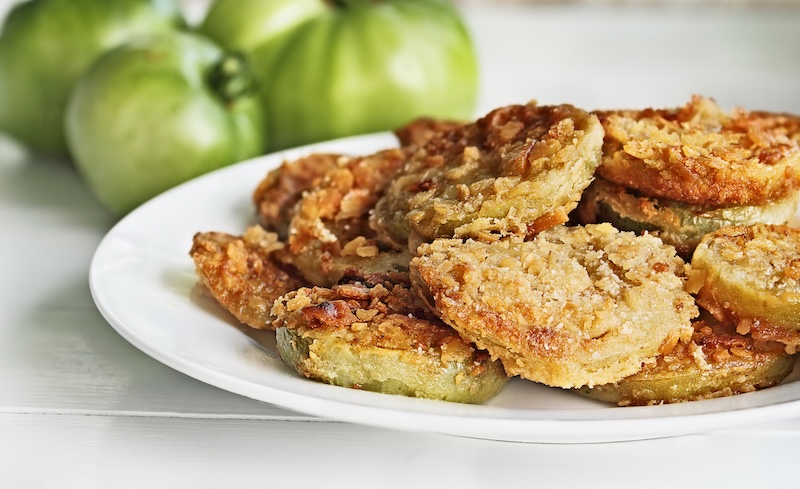 Plate of fresh fried green tomatoes. Tomatoes have been coated in cracker crumbs before frying. Extreme shallow depth of field with selective focus.