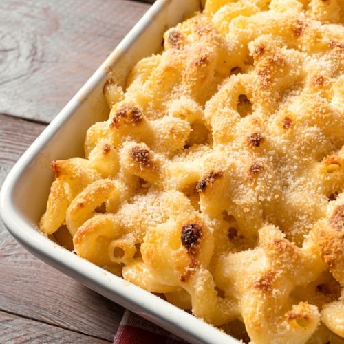 Traditional southern Mac and cheese with breadcrumbs close up. Homemade cheesy and creamy pasta casserole with meat for dinner.