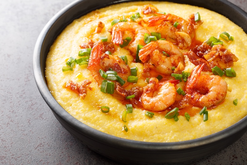Bowl with fresh tasty shrimp and grits on a dark concrete background. American cuisine. Horizontal