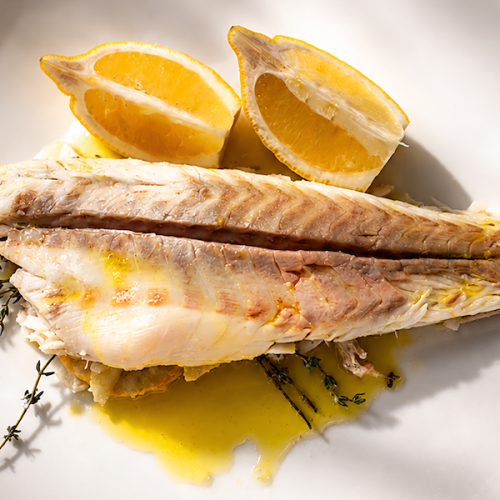 Salt-crusted branzino served with lemon on white plate