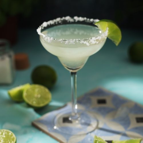 Classic margarita with salted rim and lime wedge on cocktail glass