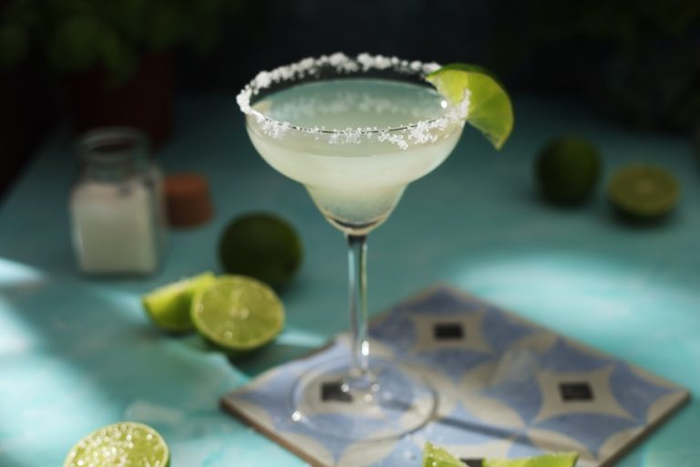 Classic margarita with salted rim and lime wedge on cocktail glass