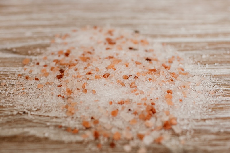 Epsom and Himalayan salt pile on wooden backdrop