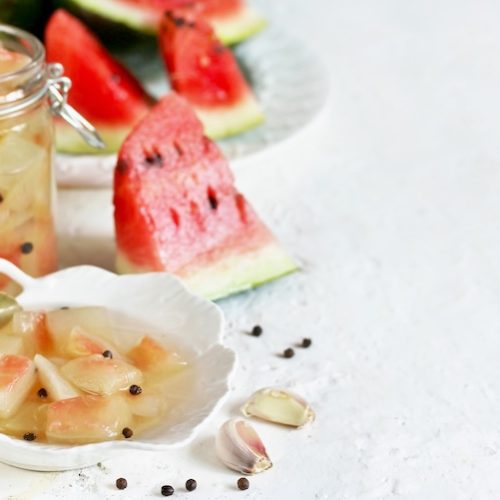 Homemade pickled watermelon rind in glass jar with peppercorns