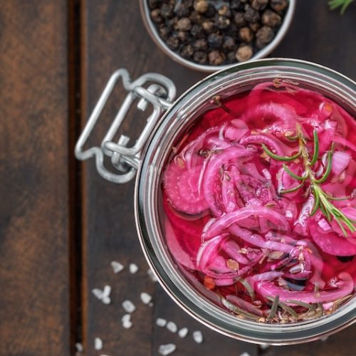 Bright pink pickled red onions in glass jar
