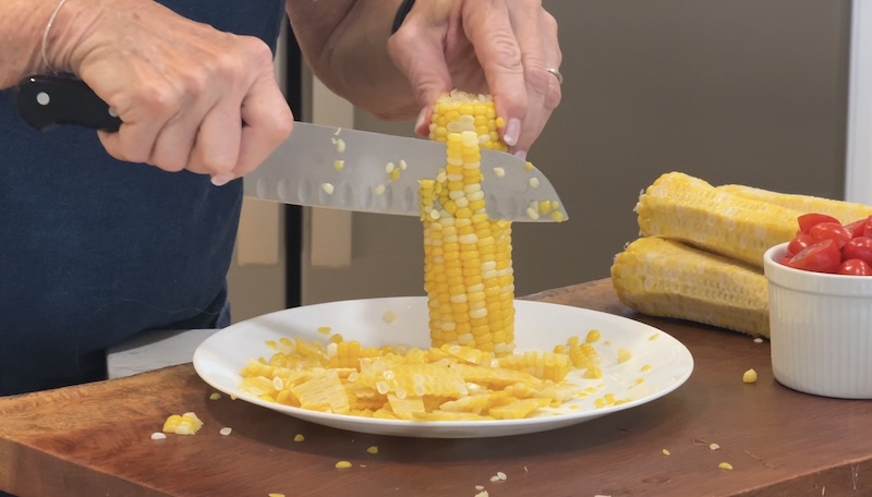Fresh sweet corn being sliced from the cob for summer salad
