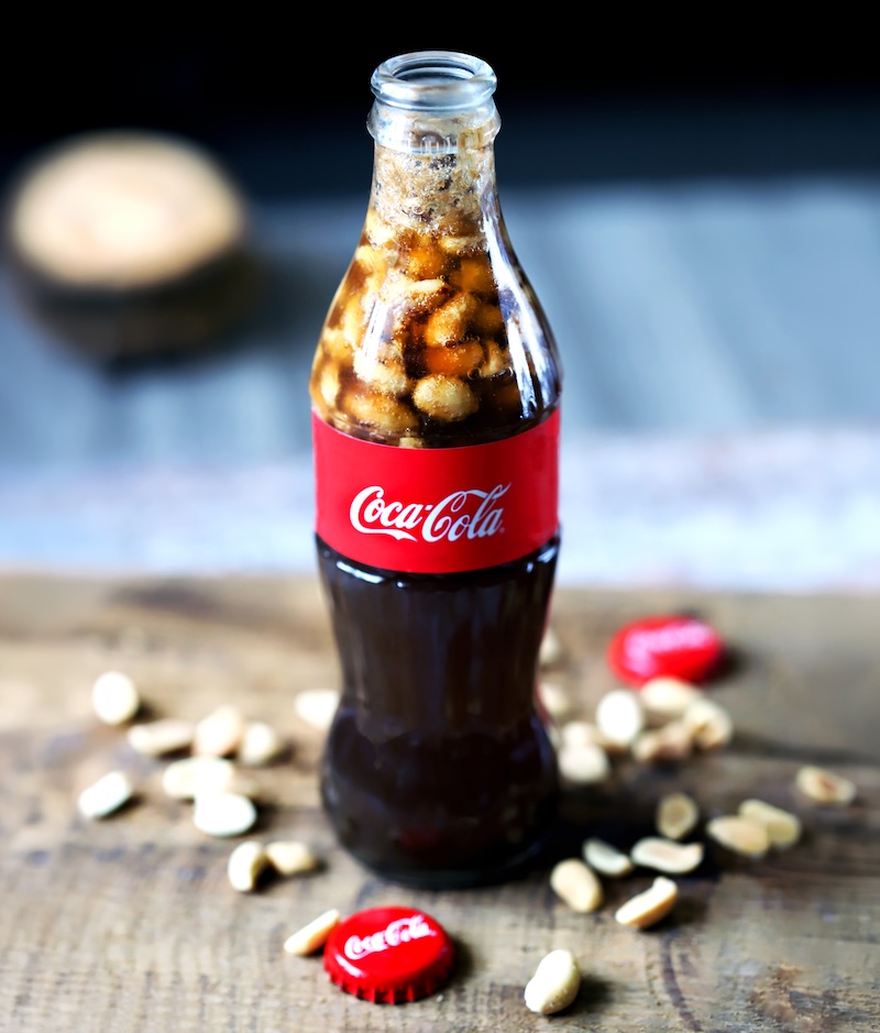 Glass bottle of Coca-Cola filled with salted peanuts