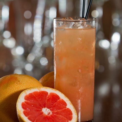 greyhound cocktail served in a tall glass on a busy out of focus bar