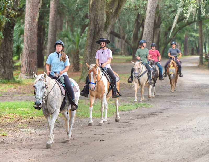 Friends horseback riding through the Sea Pines Forest Preserve at Lawton Stables.