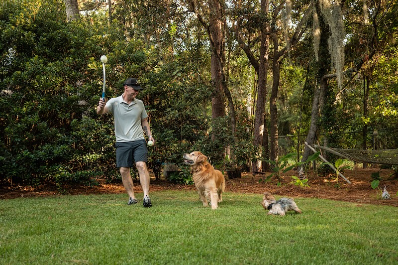Bear retrieves a toy while training and playing outdoors with Drew Kaufman.
