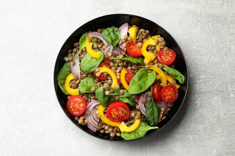 Tasty salad with lentils and vegetables on grey table, top view