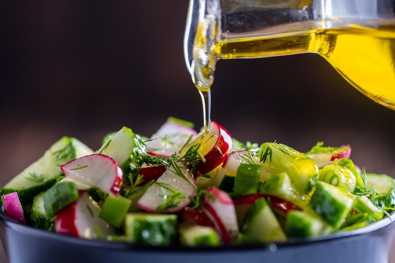 Fresh salad being topped with olive oil during a cooking workshop at Hilton Head Olive Oils & Balsamics.